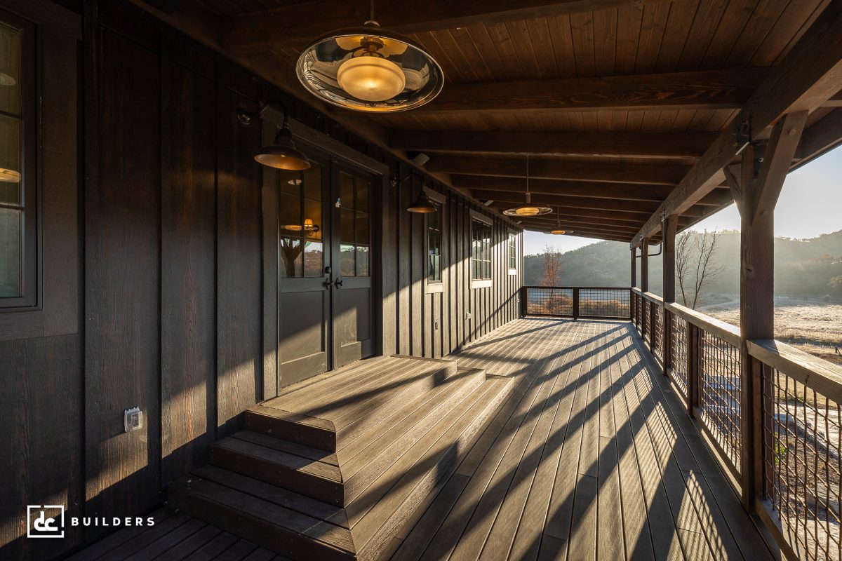 Dark brown wooden covered porch overlooking desert mountains.