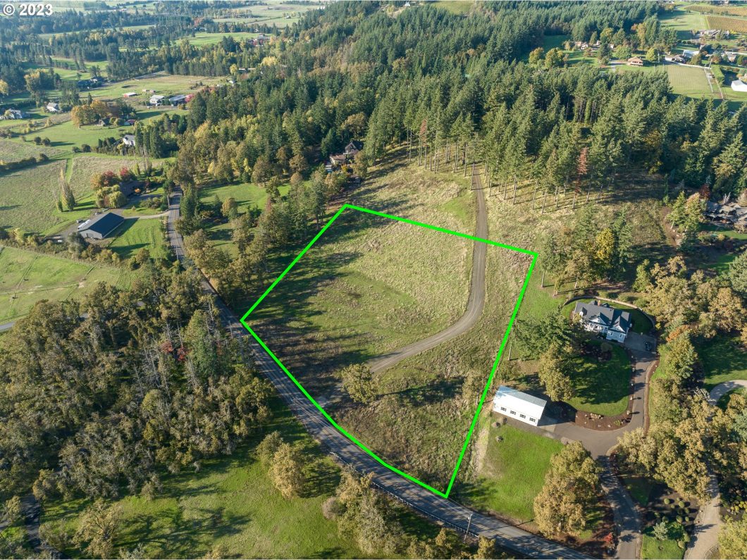 Aerial view of a rural property with outlined boundaries, featuring a winding road, trees, and open land.