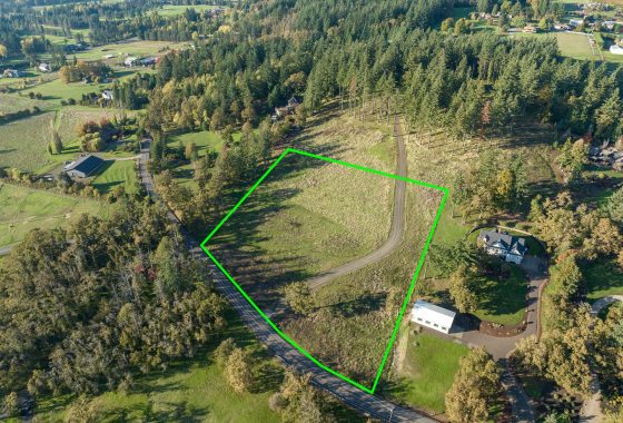 Aerial view of a rural property with outlined boundaries, featuring a winding road, trees, and open land.